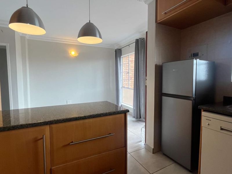 Open-plan kitchen and dining area featuring granite countertops, built-in cabinetry, and tiled flooring, offering a functional layout for modern living.