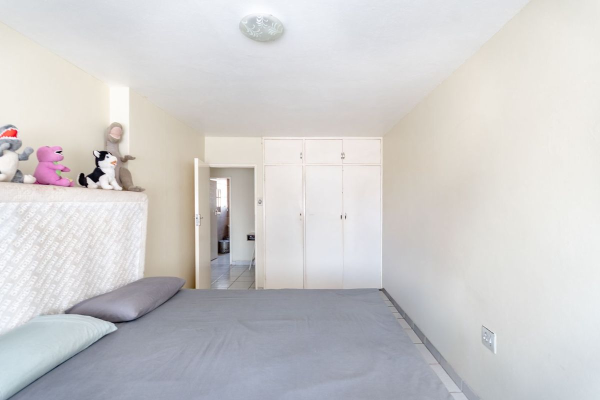 A bedroom featuring built-in floor-to-ceiling cupboards, tiled flooring, and a doorway leading to an adjacent room.