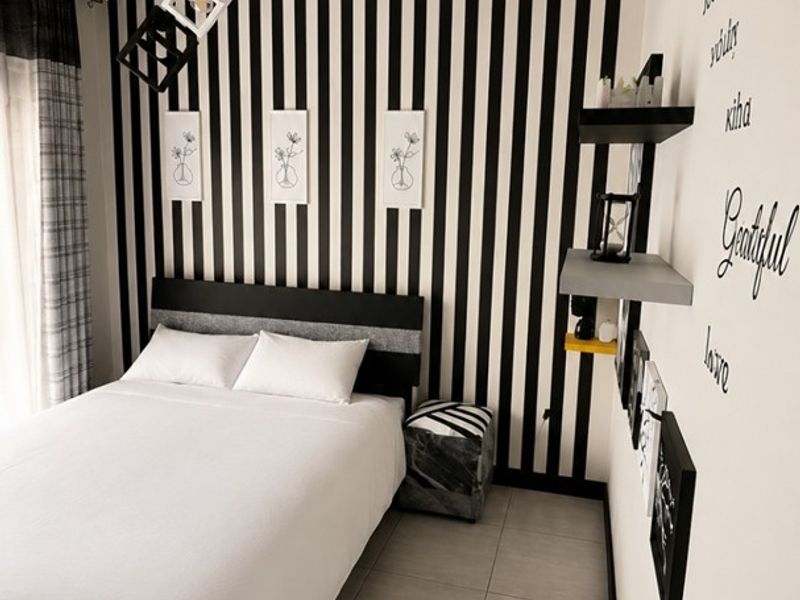 A bedroom featuring tiled flooring and modern pendant lighting, characterized by bold black and white striped wall and ceiling decor.
