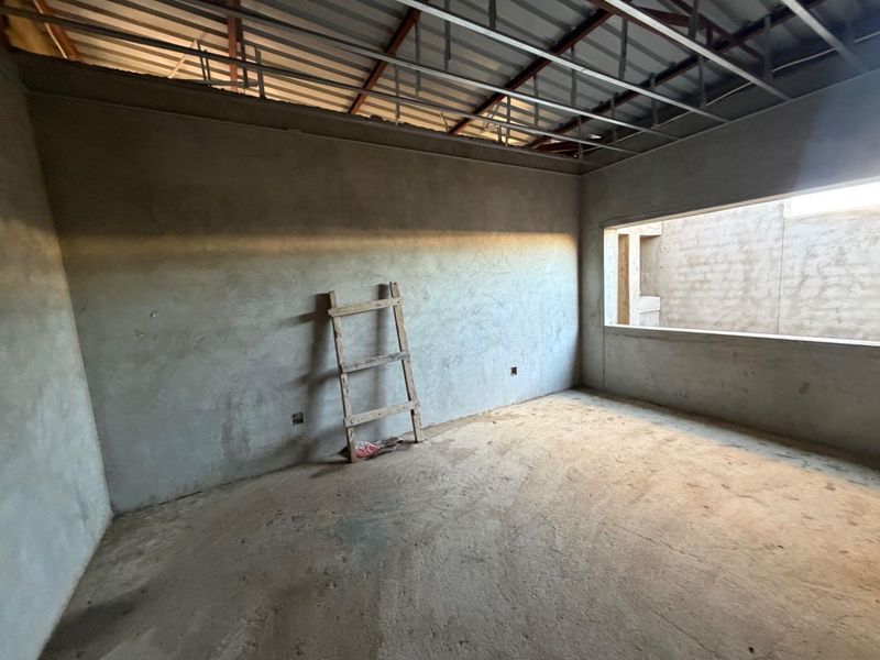 An unfinished bedroom space featuring exposed ceiling joists, plastered walls, and concrete flooring, offering a blank canvas for renovation and interior finishing.