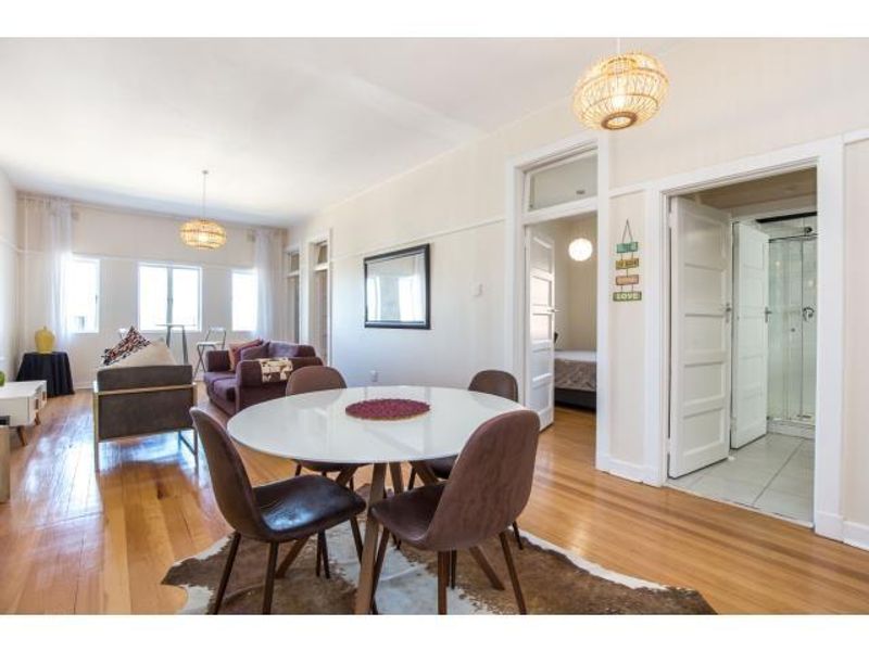 Spacious open-plan living and dining area featuring polished hardwood flooring, high ceilings, and classic architectural door frames leading to adjacent rooms.