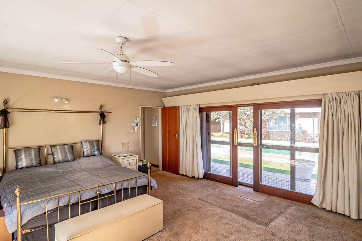 Spacious bedroom featuring large sliding glass doors that provide direct access to the outdoor pool area and garden.
