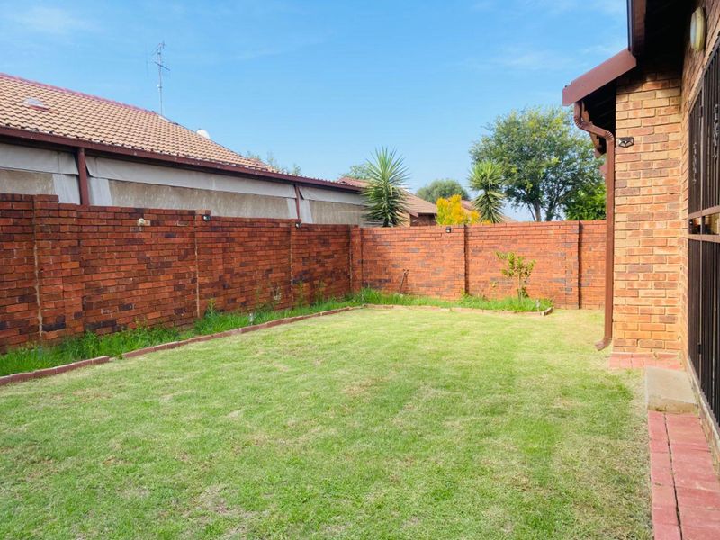 A private rear garden featuring a well-maintained lawn enclosed by a sturdy face brick boundary wall.