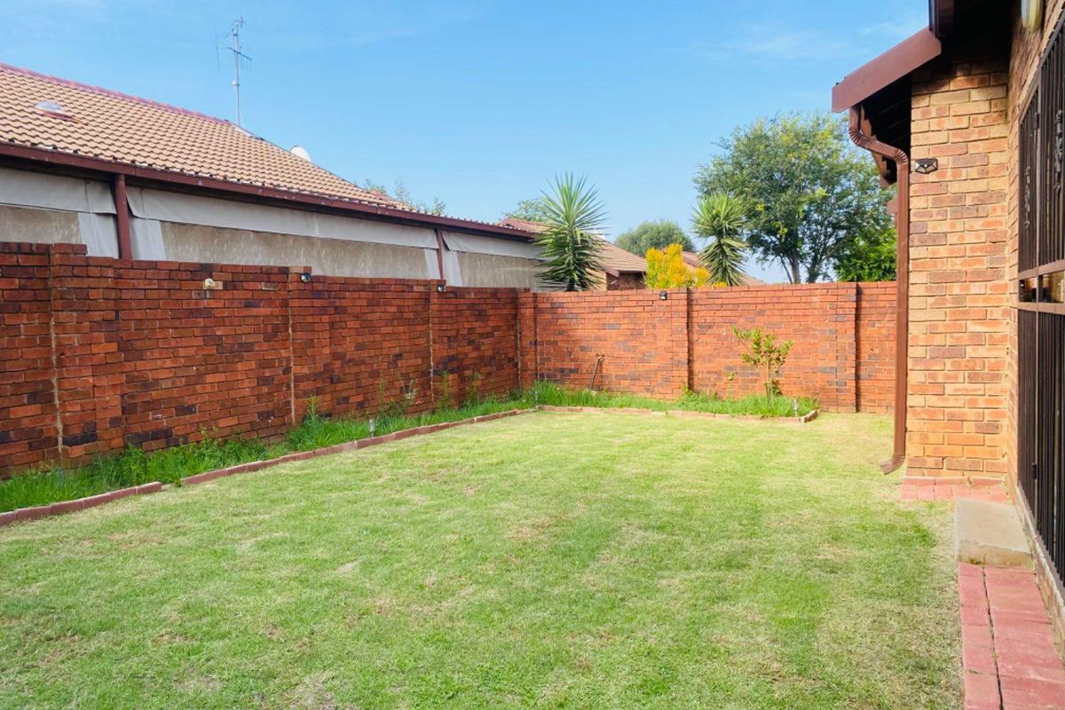 A private rear garden featuring a well-maintained lawn enclosed by a sturdy face brick boundary wall.