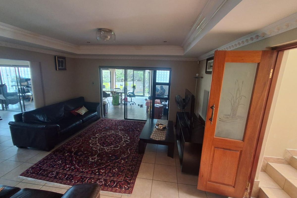 Spacious living room featuring tiled flooring, decorative ceiling cornices, and sliding glass doors providing direct access to the outdoor patio area.