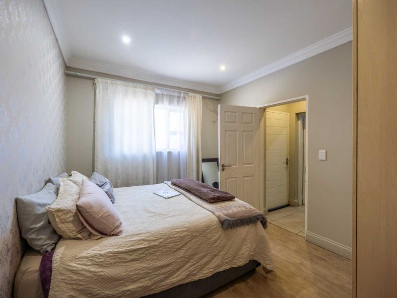 A well-maintained bedroom featuring laminate flooring, recessed downlighting, crown molding, and a built-in wardrobe, offering a clean and functional living space.