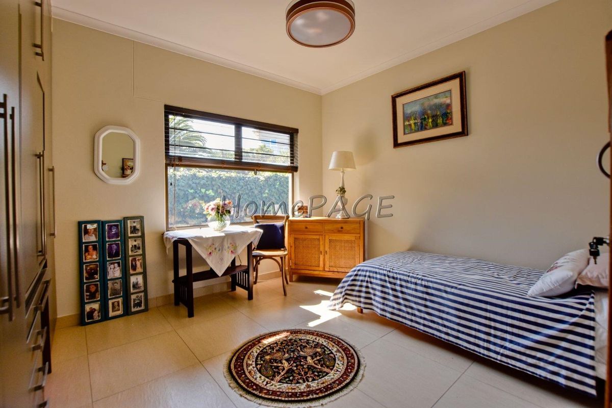 A well-lit bedroom featuring neutral tiled flooring and built-in storage cupboards, offering a functional and comfortable living space.