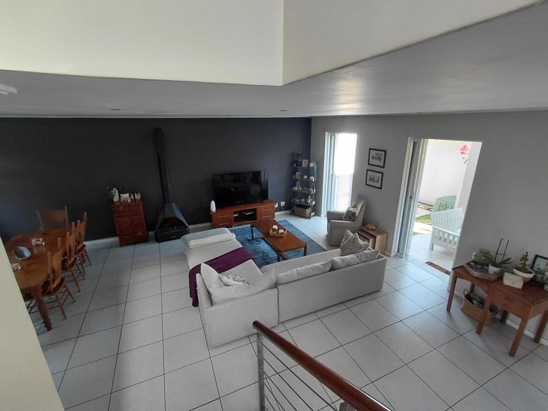 Spacious open-plan living and dining area featuring tiled floors, a modern freestanding fireplace, and direct access to an outdoor patio space.