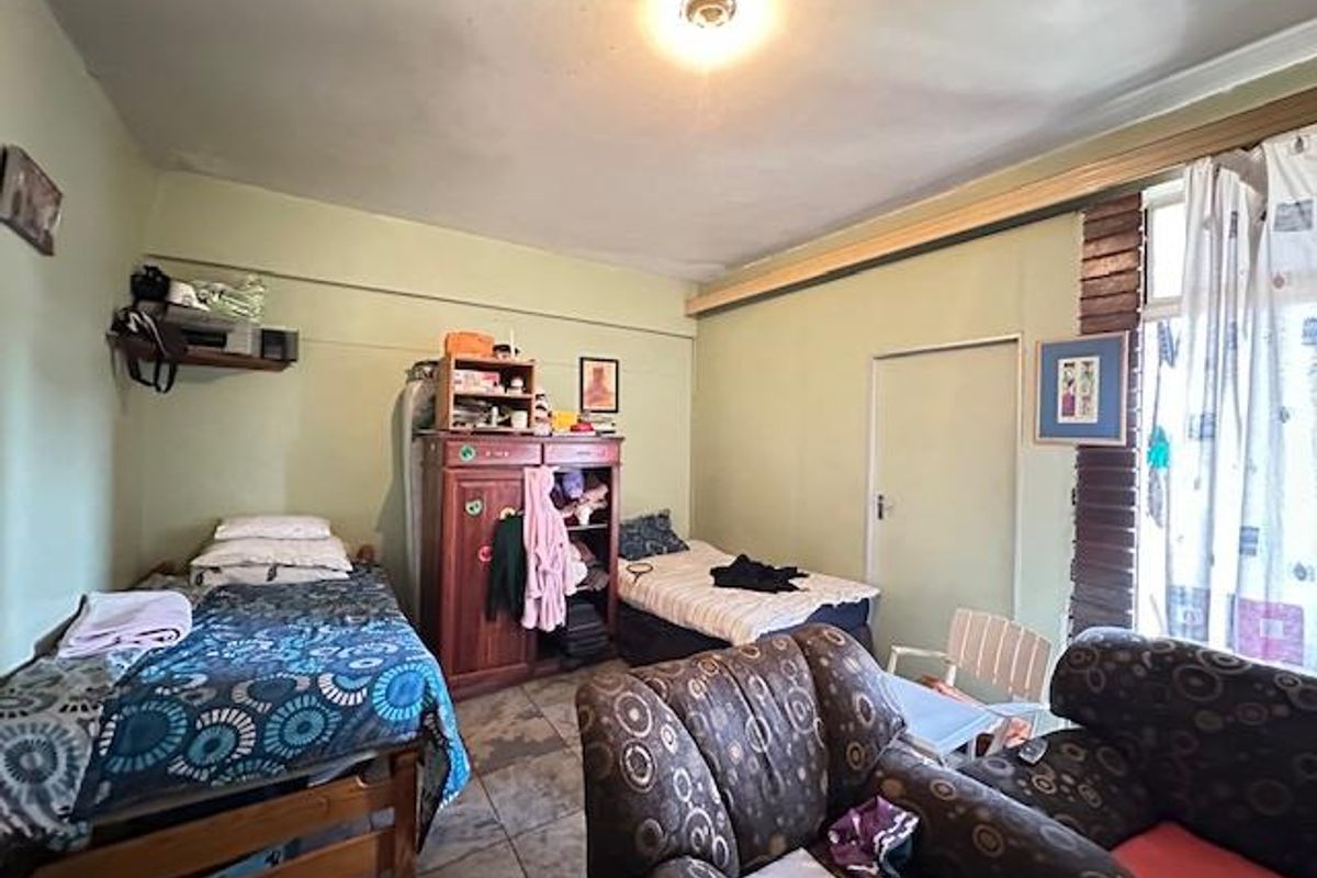 A bedroom featuring tiled flooring and direct access to an outdoor area, providing a functional space with potential for modernization.
