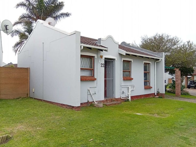 Front elevation of a single-story townhouse featuring a tiled roof, brick base, and security gate entrance.