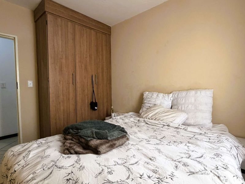 A bedroom featuring a wood-finish built-in wardrobe and neutral wall tones, offering a functional space with potential for cosmetic updates.