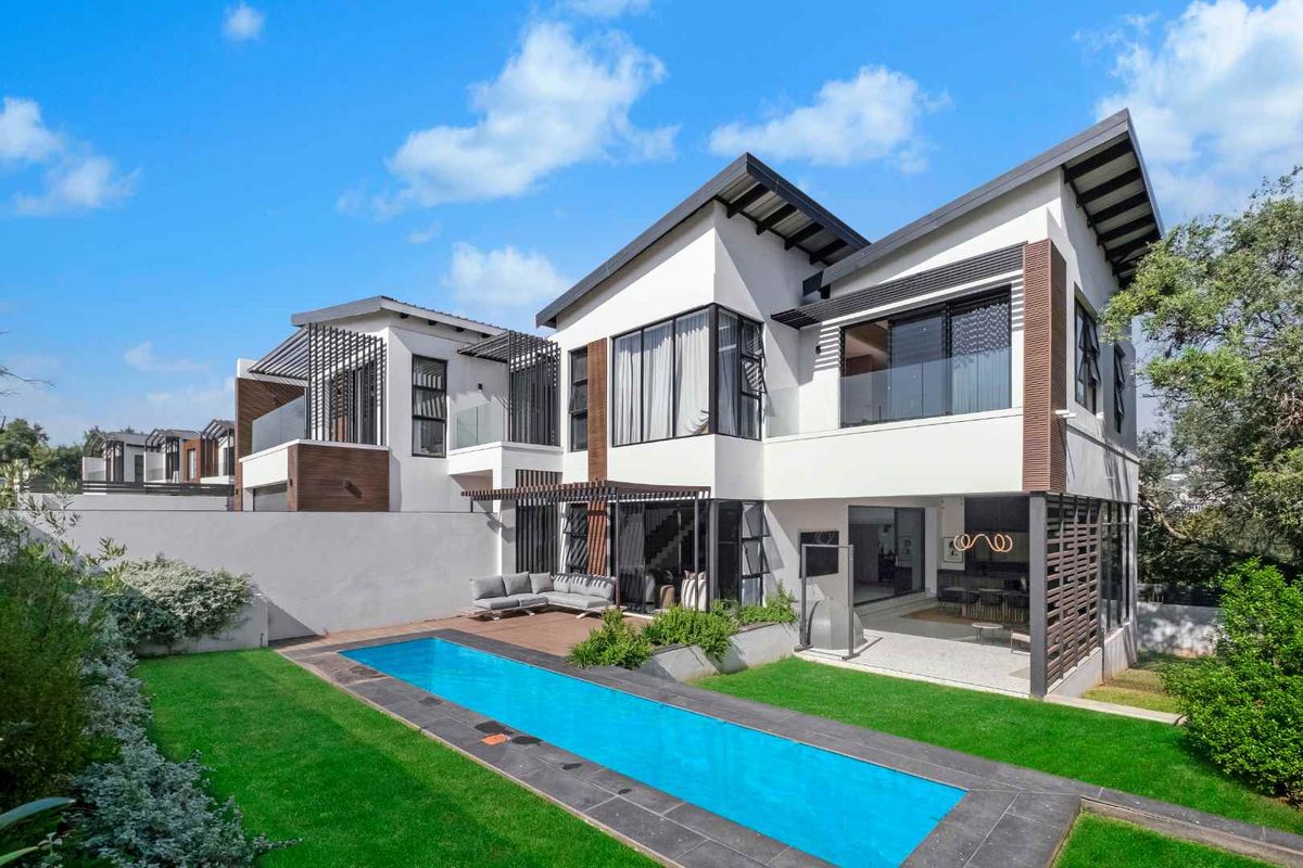 Modern double-story residence featuring a sleek architectural design, private swimming pool, landscaped garden, and integrated covered patio area for outdoor living.