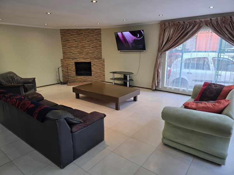 Spacious living room featuring tiled flooring, recessed downlights, and a stone-clad fireplace, providing a comfortable and functional family area.
