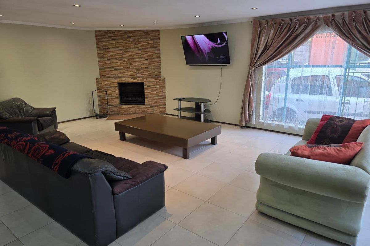 Spacious living room featuring tiled flooring, recessed downlights, and a stone-clad fireplace, providing a comfortable and functional family area.