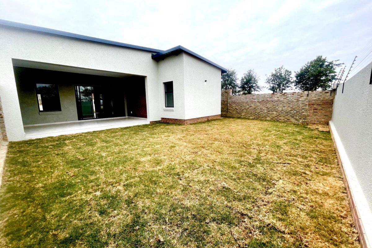 A rear view of the townhouse featuring a covered patio area, a private garden, and perimeter brick walling with electric fencing.