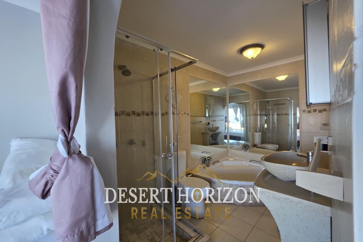 A bathroom featuring a glass-enclosed shower, a corner bathtub, a pedestal basin, and large wall-mounted mirrors.