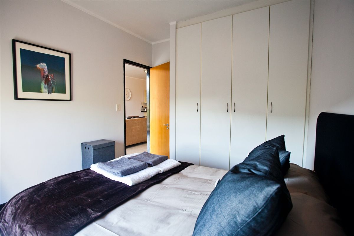 A well-maintained bedroom featuring ample built-in cupboard storage and neutral finishes, providing a clean and functional living space.