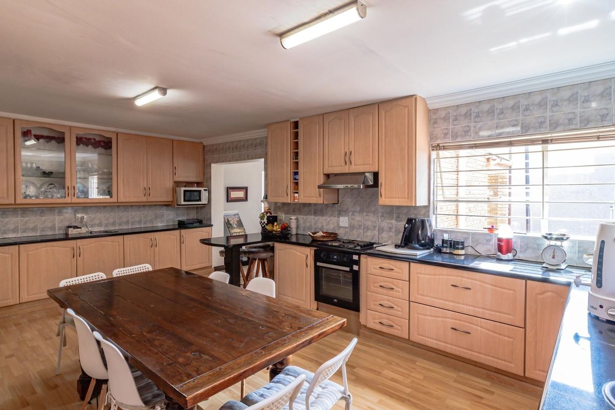 Spacious kitchen featuring light wood cabinetry, dark countertops, integrated oven, extractor fan, and a dedicated dining area with laminate flooring.