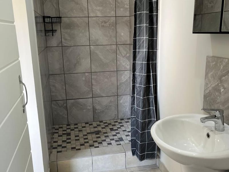A compact bathroom featuring a tiled shower enclosure with a pedestal basin and modern fixtures.