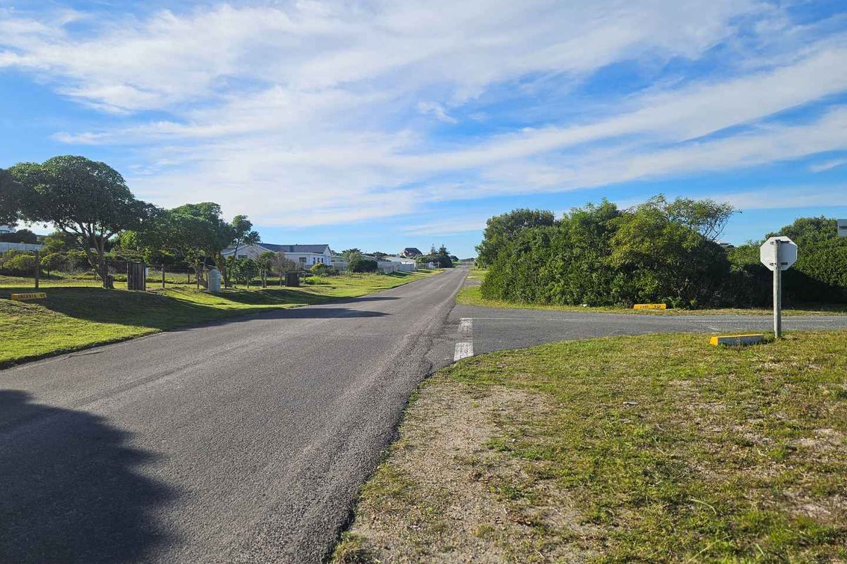 A clear street view showing the paved road access and surrounding landscape of the residential area.