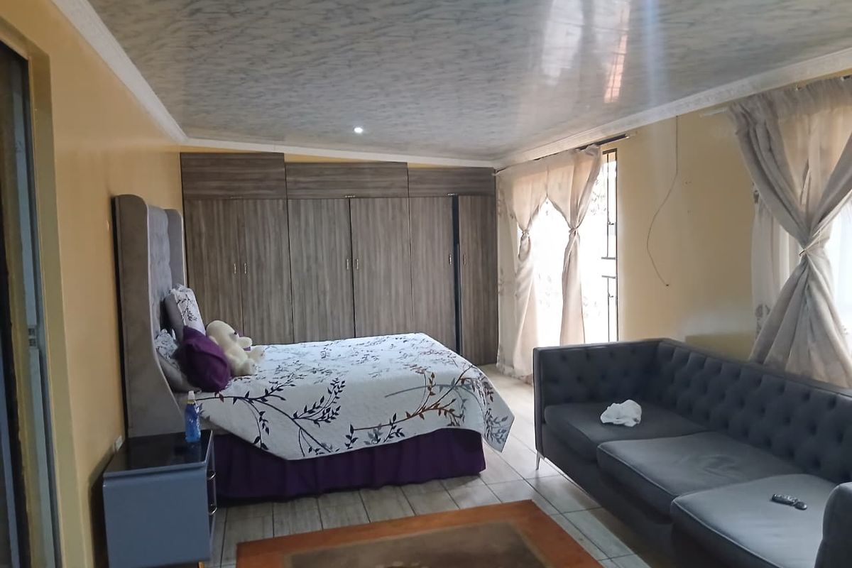 Spacious bedroom featuring extensive built-in wooden cabinetry, tiled flooring, and large windows allowing for natural light.