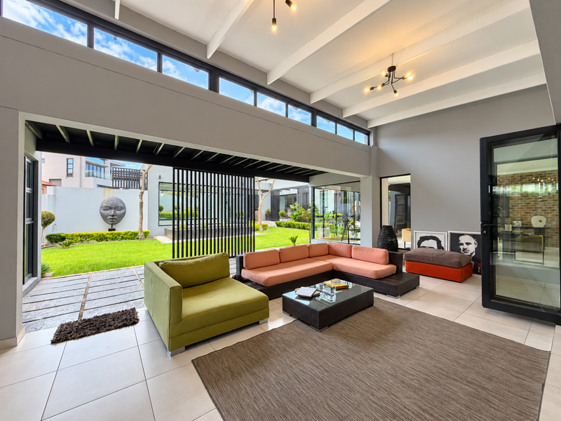 Spacious living room featuring a vaulted ceiling with exposed beams, clerestory windows, and large sliding doors that open seamlessly to the garden.