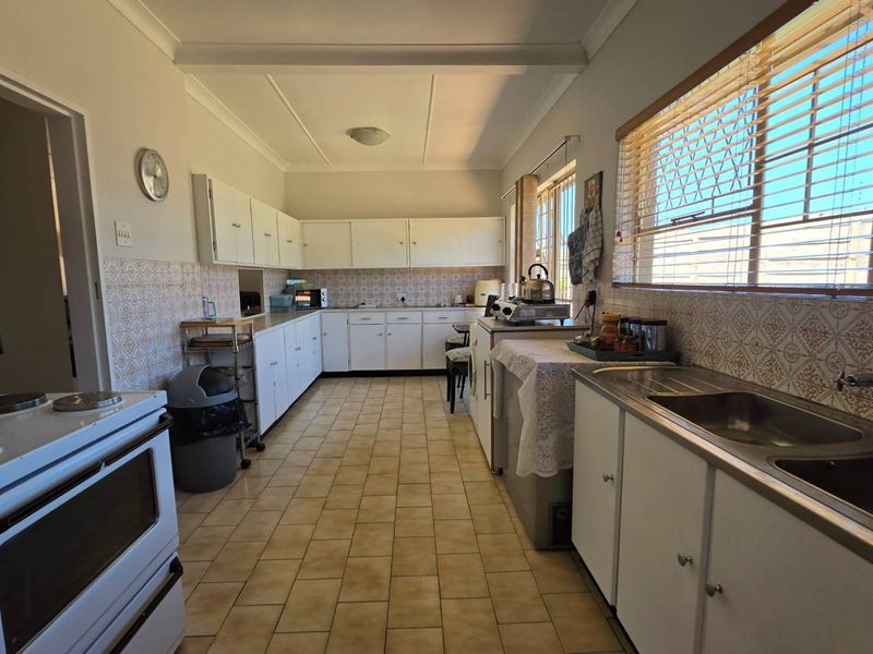 A functional kitchen featuring white built-in cabinetry, tiled backsplash, and tiled flooring, offering a classic layout with ample storage and preparation space.