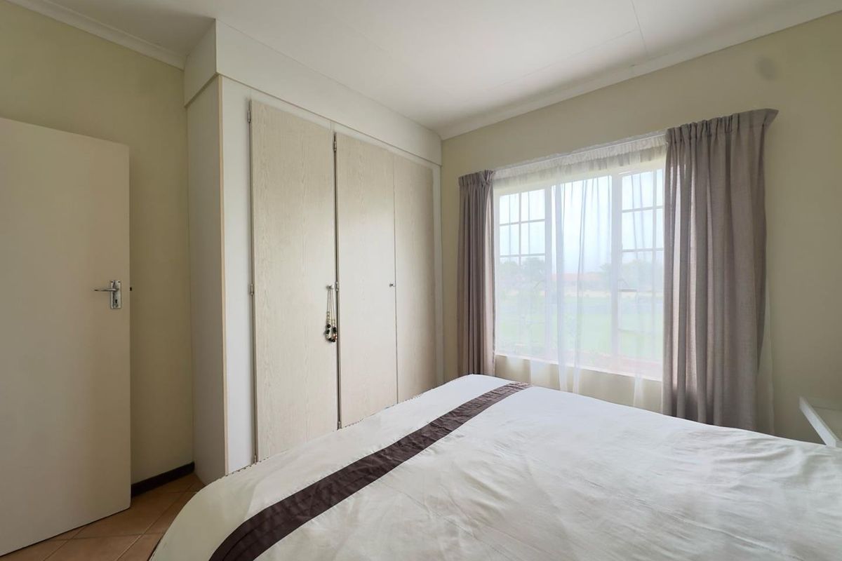 A bright bedroom featuring built-in cupboards and large windows that allow for natural light.