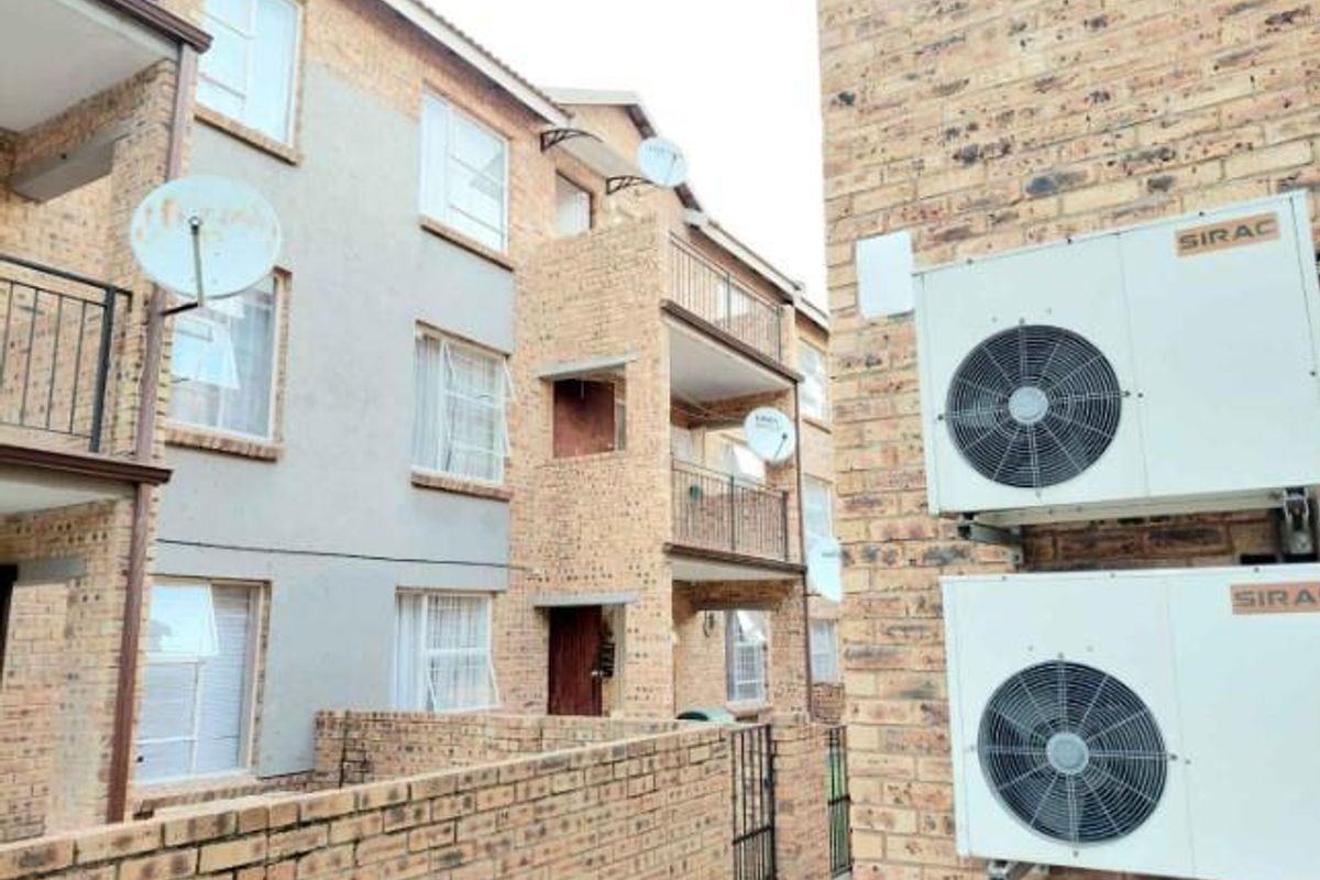 Exterior view of a multi-story apartment complex featuring face-brick facade, private balconies with metal railings, and wall-mounted air conditioning units.