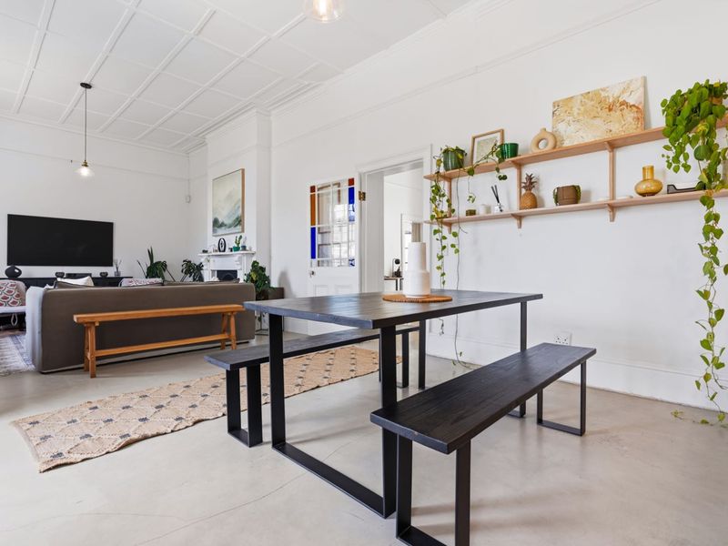 Spacious open-plan living and dining area featuring a coffered ceiling, polished concrete floors, and a classic fireplace with stained glass door detailing.