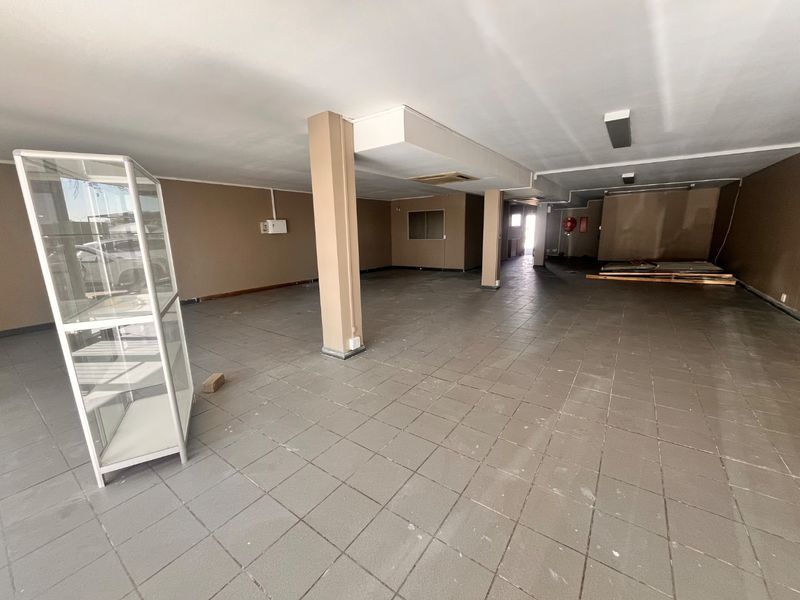 A spacious, open-plan retail area featuring tiled flooring, structural support columns, and basic lighting, suitable for various commercial business configurations.