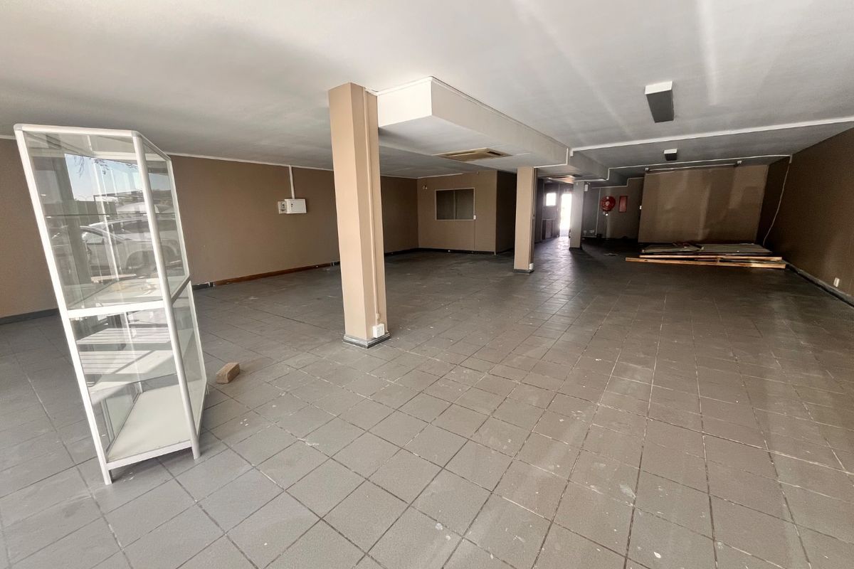 A spacious, open-plan retail area featuring tiled flooring, structural support columns, and basic lighting, suitable for various commercial business configurations.