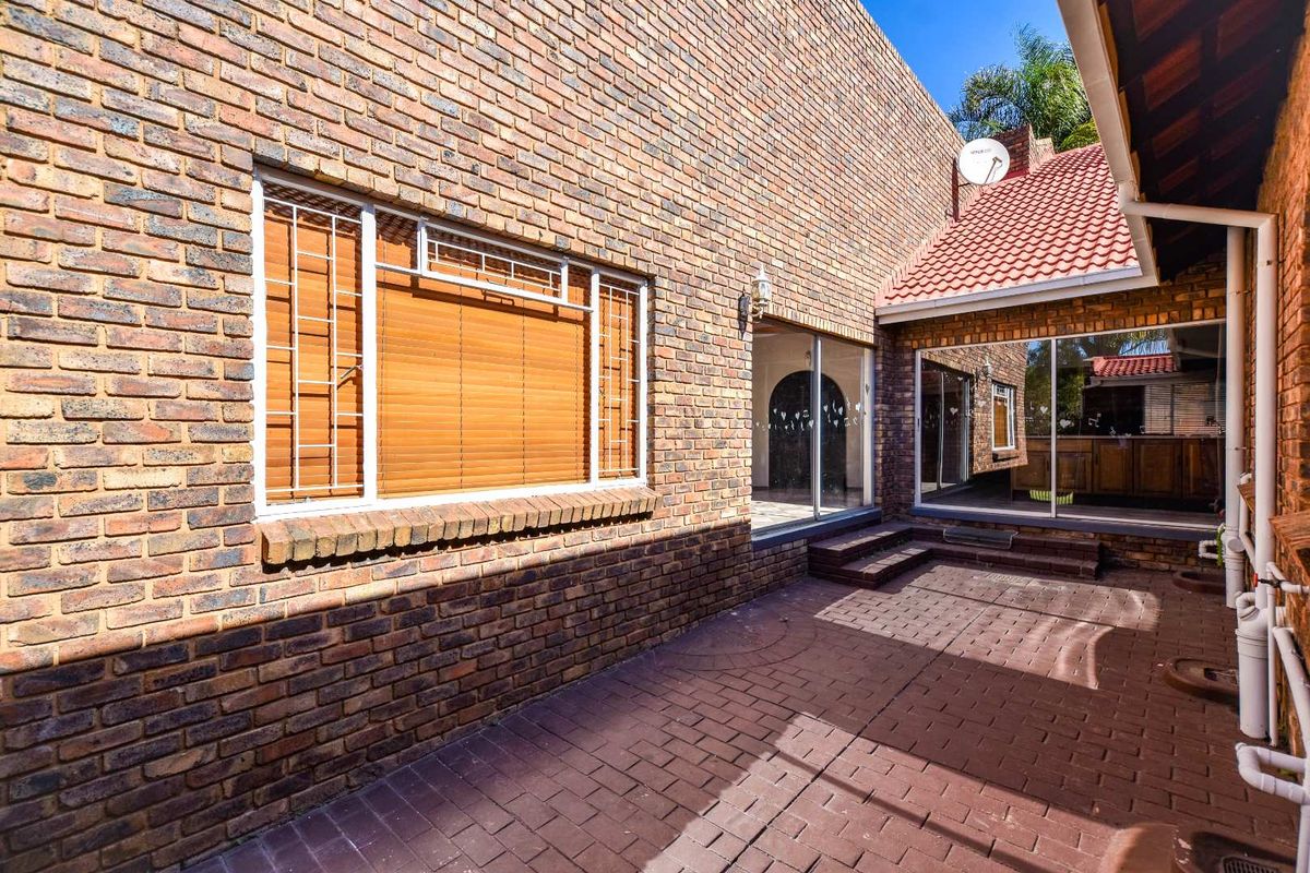 A private rear courtyard featuring face brick walls, paved flooring, and large sliding glass doors providing access to the interior living spaces.