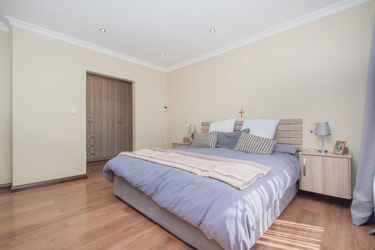 A well-maintained bedroom featuring laminate flooring, recessed ceiling lighting, crown molding, and built-in wooden cabinetry.