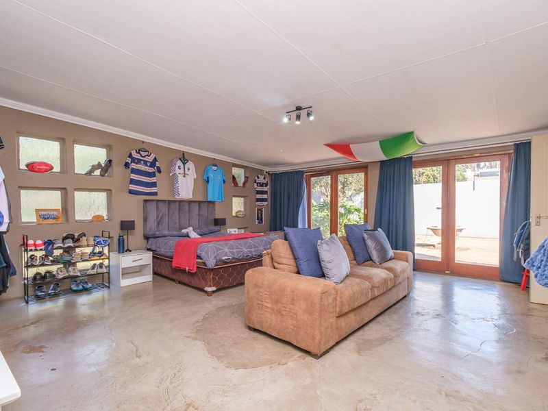 Spacious bedroom featuring polished concrete floors, unique recessed wall niches, and direct access to the garden through timber-framed glass sliding doors.