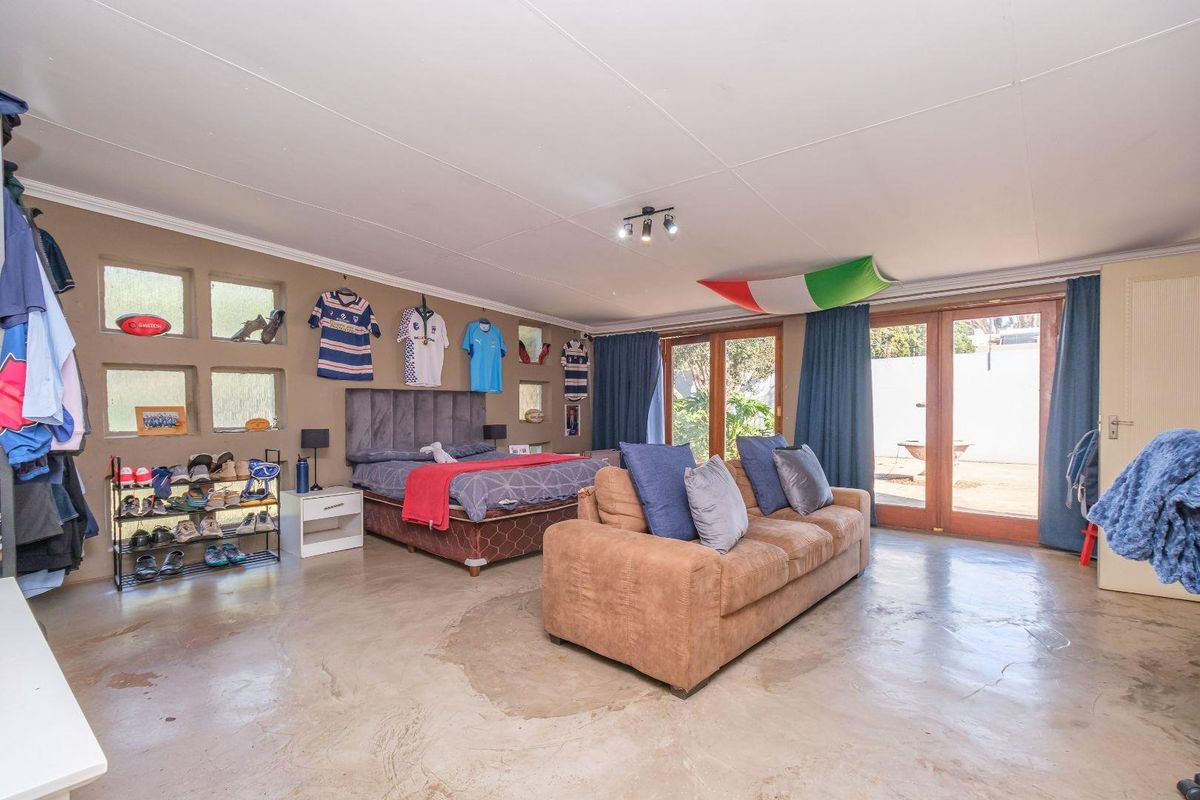 Spacious bedroom featuring polished concrete floors, unique recessed wall niches, and direct access to the garden through timber-framed glass sliding doors.