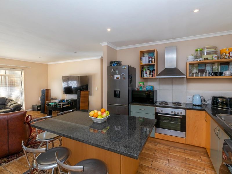 Open-plan living area featuring a modern kitchen with granite countertops, built-in appliances, and a central island, seamlessly flowing into the adjacent lounge space.