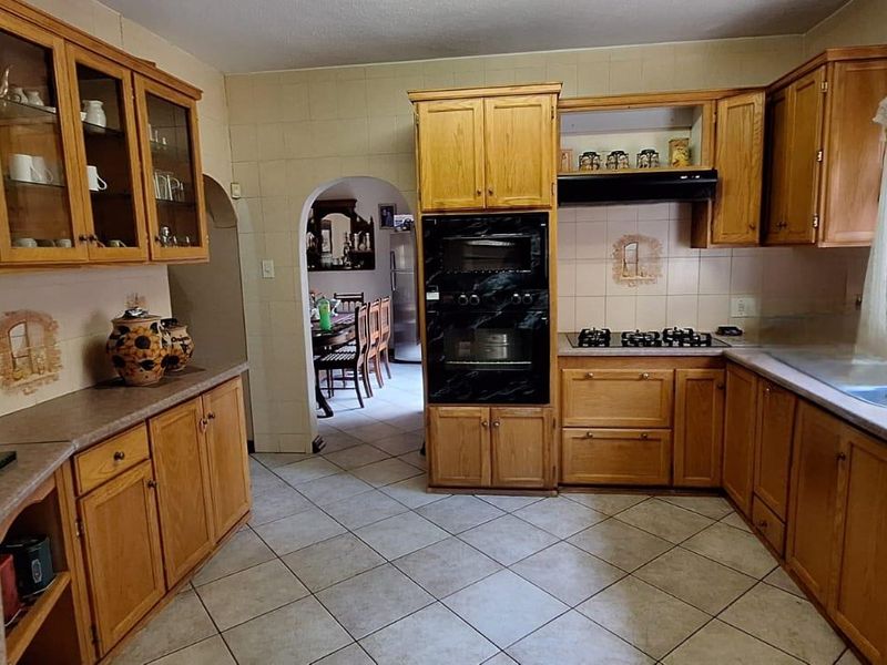 A traditional kitchen featuring wooden cabinetry, built-in oven, gas hob, and tiled flooring, offering a functional layout with potential for modern updates.
