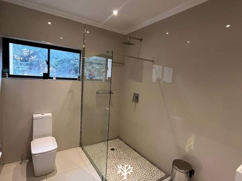 Modern bathroom featuring a walk-in shower with a pebble floor, glass screen, and contemporary wall-mounted shower head.