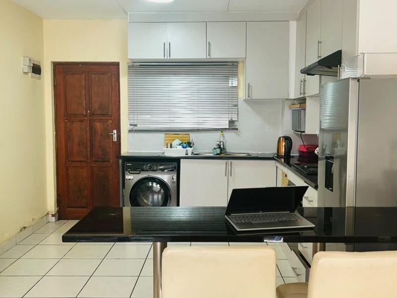 Functional kitchen featuring built-in cabinetry, laminate countertops, a breakfast bar, and tiled flooring, providing a practical layout for daily meal preparation.