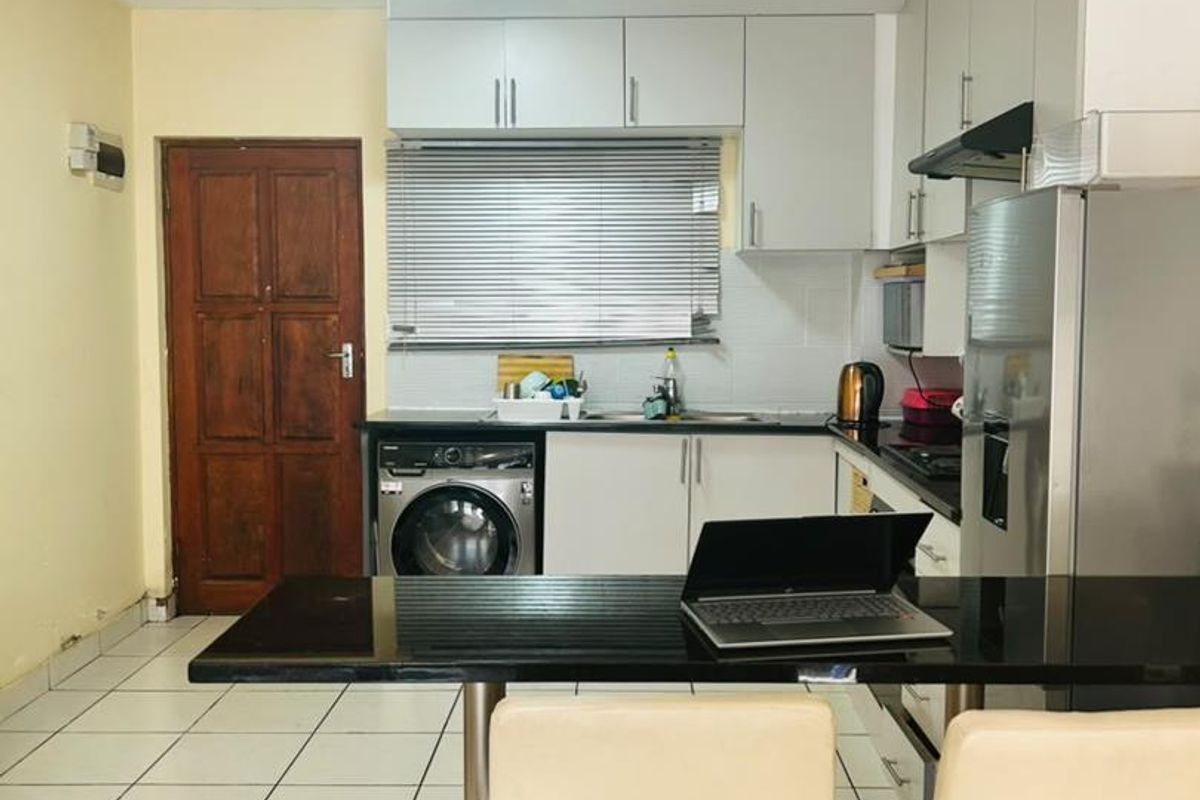 Functional kitchen featuring built-in cabinetry, laminate countertops, a breakfast bar, and tiled flooring, providing a practical layout for daily meal preparation.