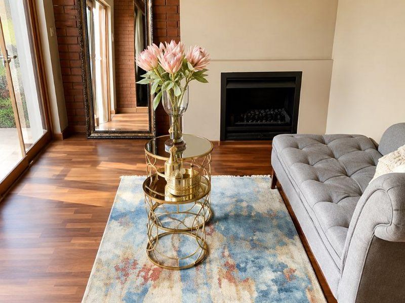 A well-maintained living room featuring a built-in fireplace, an exposed brick feature wall, and warm laminate flooring with access to an outdoor area.