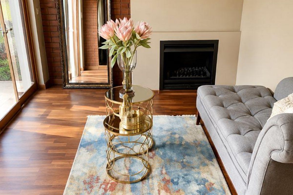 A well-maintained living room featuring a built-in fireplace, an exposed brick feature wall, and warm laminate flooring with access to an outdoor area.