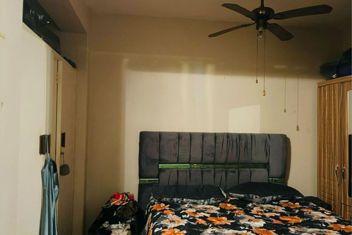 A bedroom featuring a ceiling fan and built-in wardrobe storage, providing a functional sleeping space.