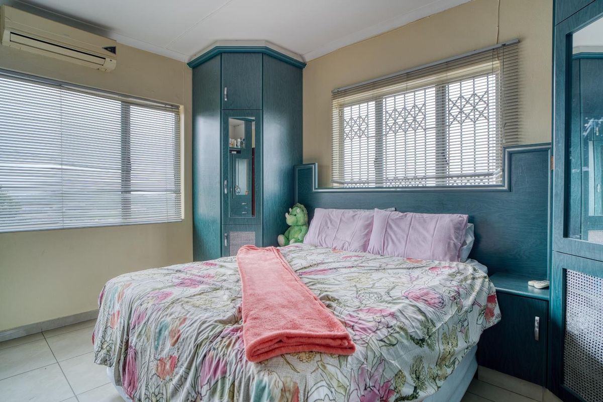 A bedroom featuring built-in cabinetry, a matching headboard, tiled flooring, and a wall-mounted air conditioning unit.