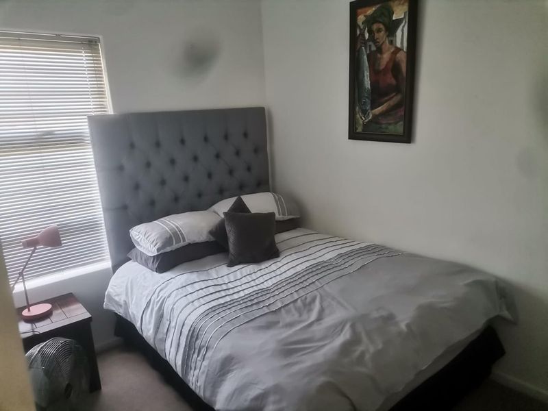 A compact bedroom featuring a window with fitted venetian blinds and neutral wall finishes.