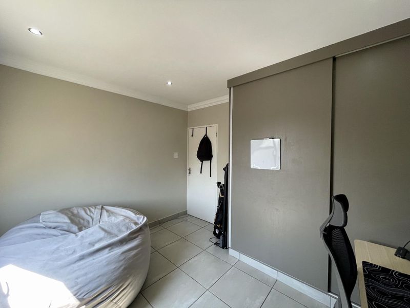 A bedroom featuring tiled flooring, recessed downlighting, and a built-in sliding door wardrobe.