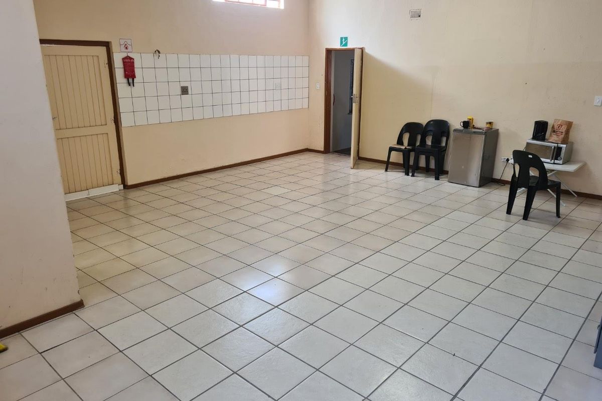 A functional utility or break room space featuring tiled flooring, a tiled splashback, and high-level window, suitable for various business or office support uses.