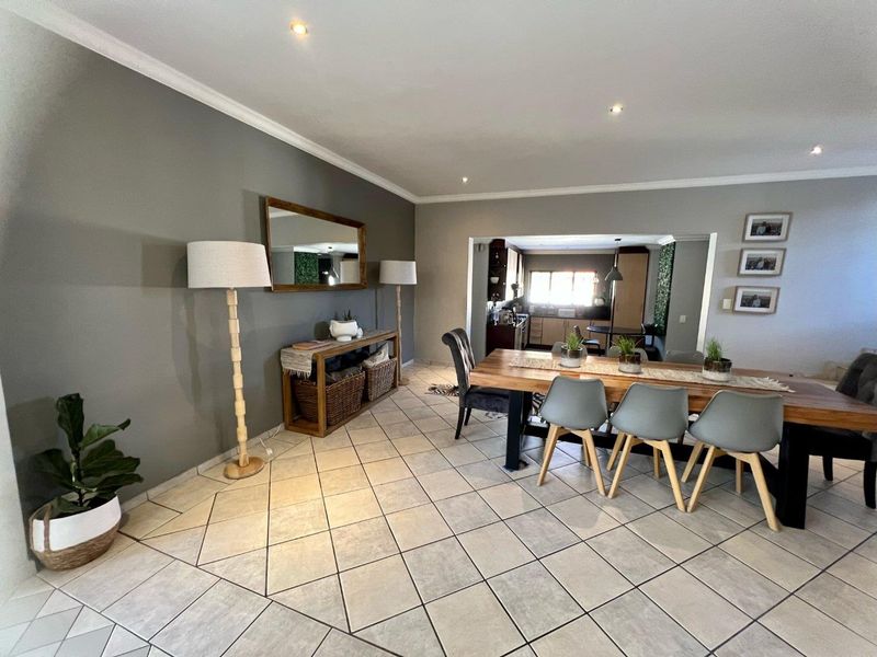 Open-plan dining area featuring neutral tiled flooring, recessed lighting, and coved cornicing, with a seamless transition into the adjacent kitchen space.