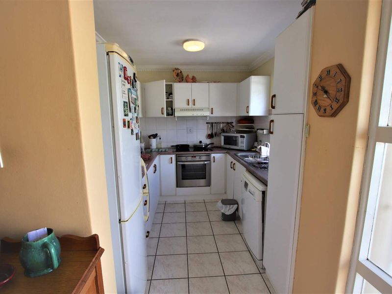 A functional galley-style kitchen featuring white cabinetry, tiled flooring, a built-in oven, and a tiled backsplash.